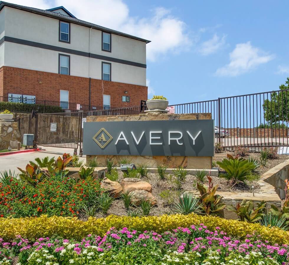 Stone sign for The Avery in front of gated entrance.