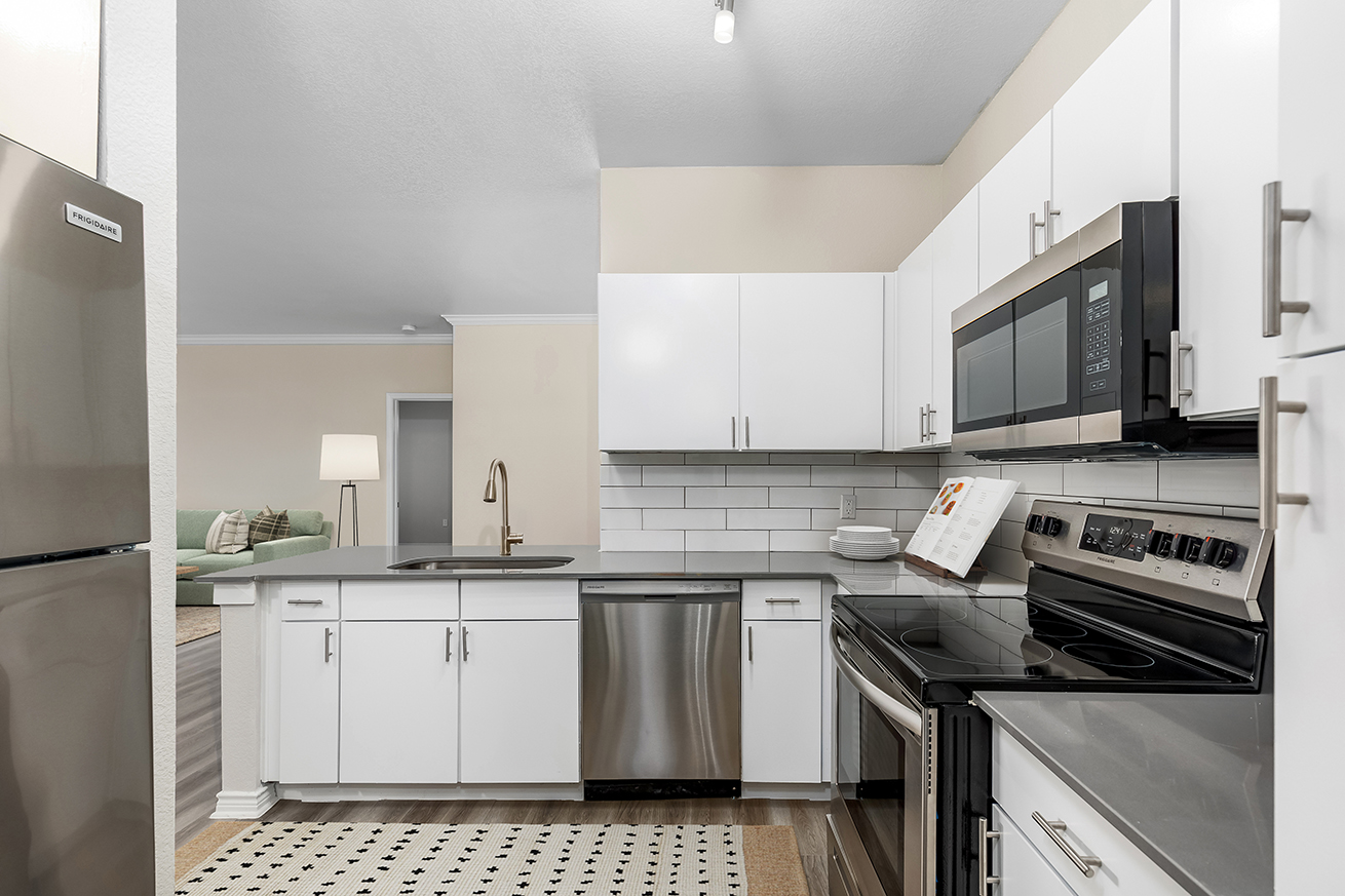 Kitchen with wood-style flooring, white cabinets, and stainless steel appliances.
